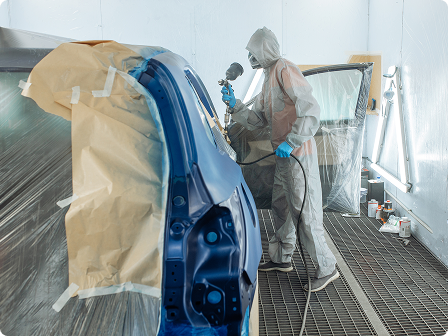 a man in uniform paints a car prepared for painting